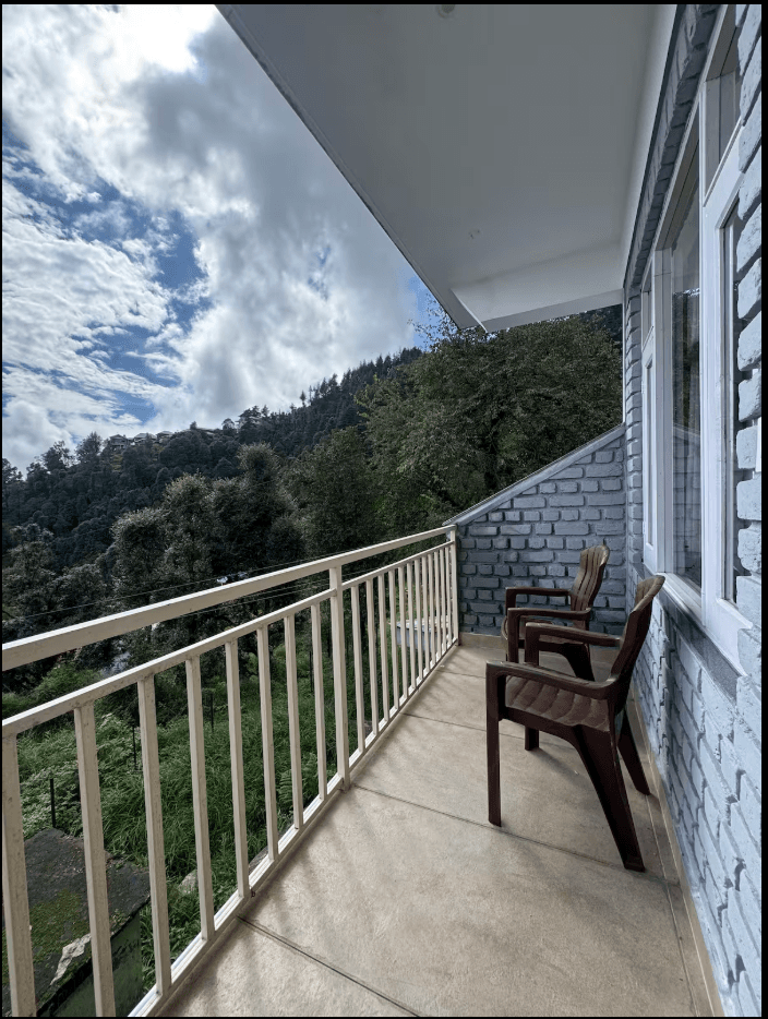 Cedar-framed homestay deck with views of the Dhauladhar range at sunrise