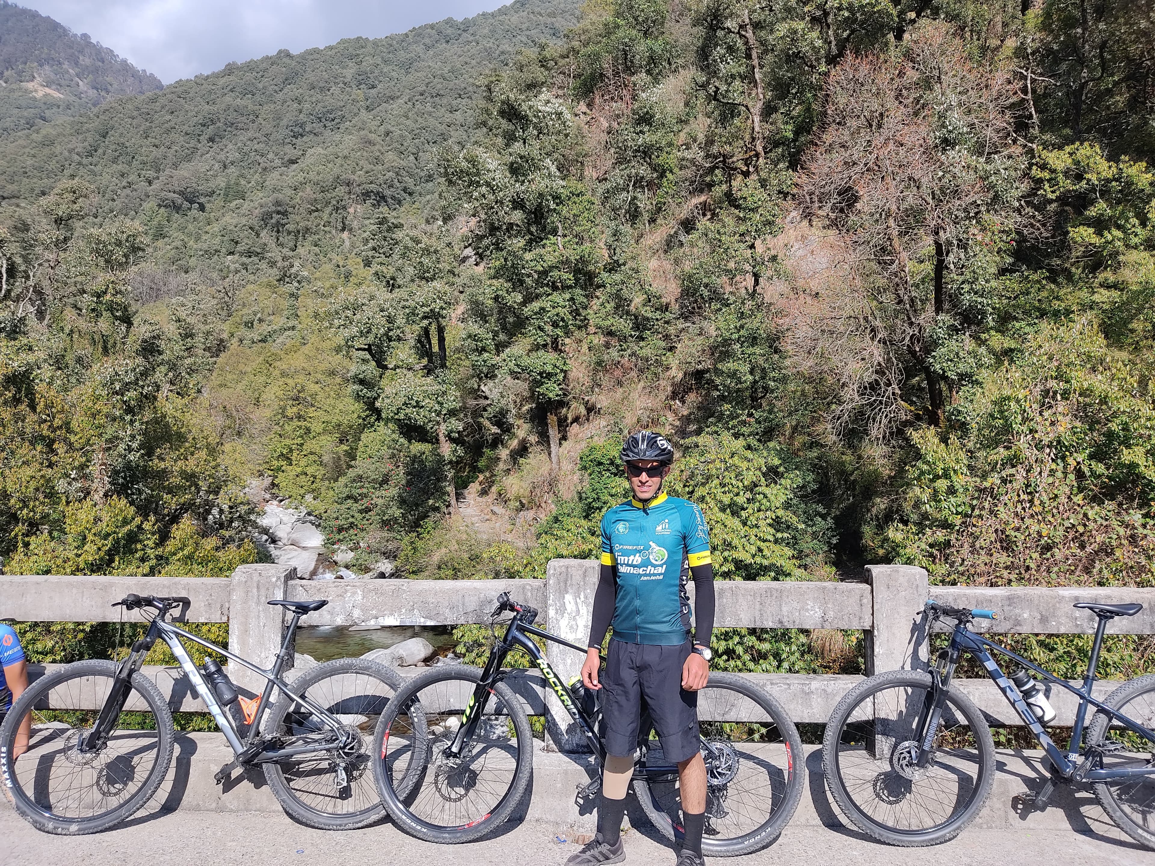 Mountain biker cornering through a deodar forest trail near Dharamkot