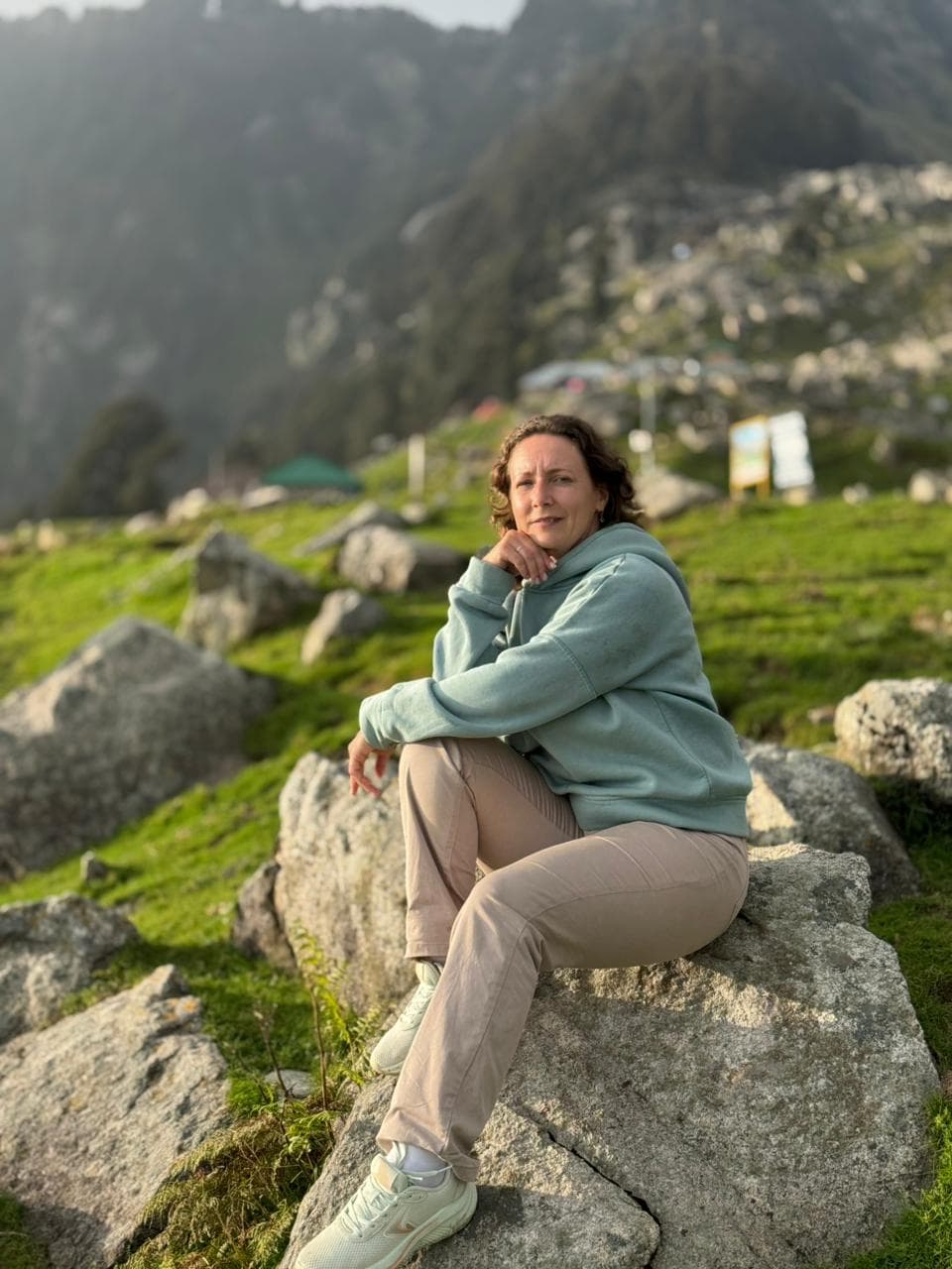 Anaya relaxing at the Dharamkot homestay terrace with pine trees behind