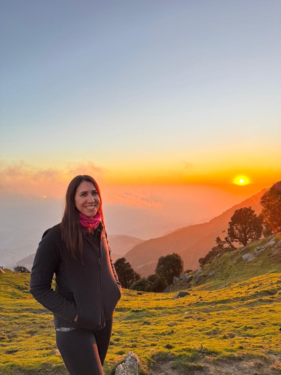 Leo smiling with trekking poles in a cedar forest near Dharamkot